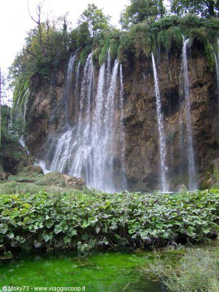 Multiple waterfalls pour down limestone cliffs over emerald lakes at Plitvice