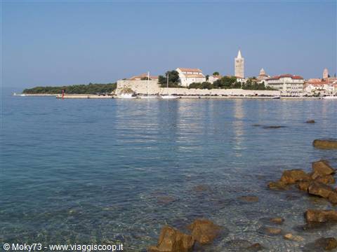 Rab old town seen from the sea, bell tower and walls over turquoise water