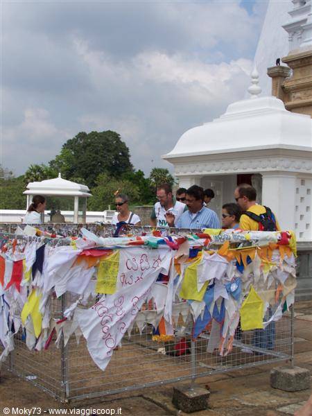 Tourists among white stupas and colorful prayer flags in the wind