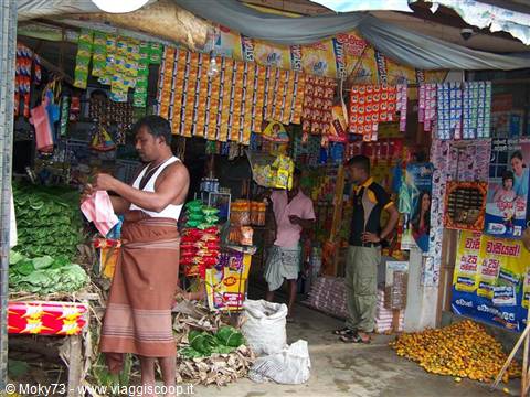 Man in lungi buying vegetables at a small busy street shop