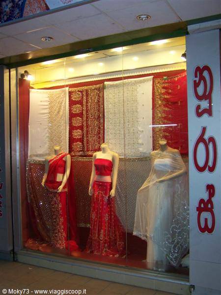Shop window with embroidered red and white saris on mannequins, Sinhala sign