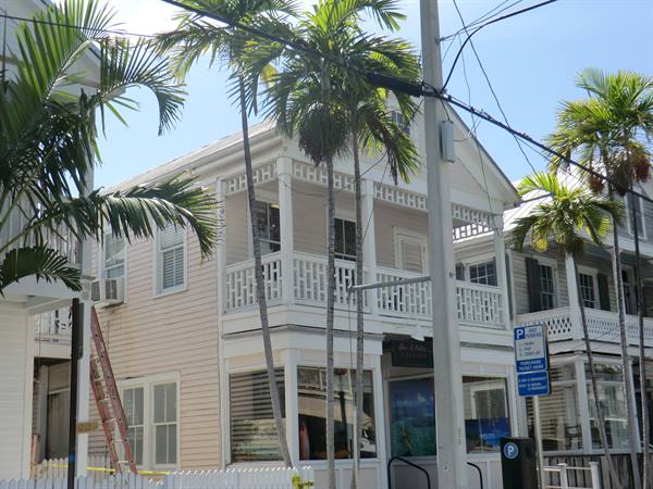 White wooden house with veranda and palm trees in Key West