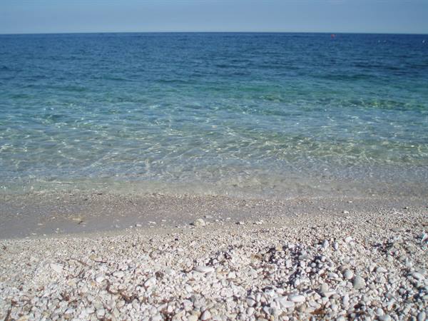 White pebble beach, clear waves fading into deep blue water