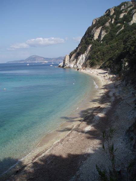 Pebble beach with white cliffs, turquoise water and anchored boats