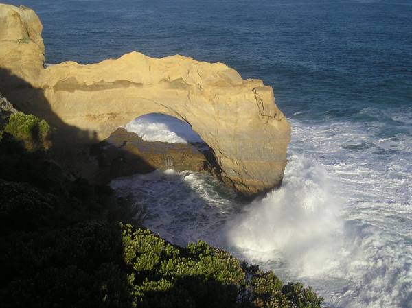 Limestone rock arch over the ocean, white waves crashing beneath, London Arch