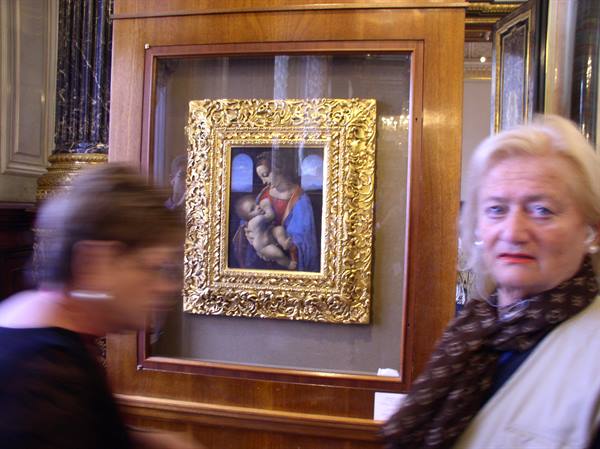 Visitors beside a Madonna and Child in a gilded frame at the museum