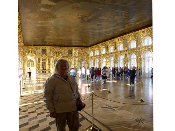 Woman in the Great Hall of Catherine Palace, gilded stucco and visitors