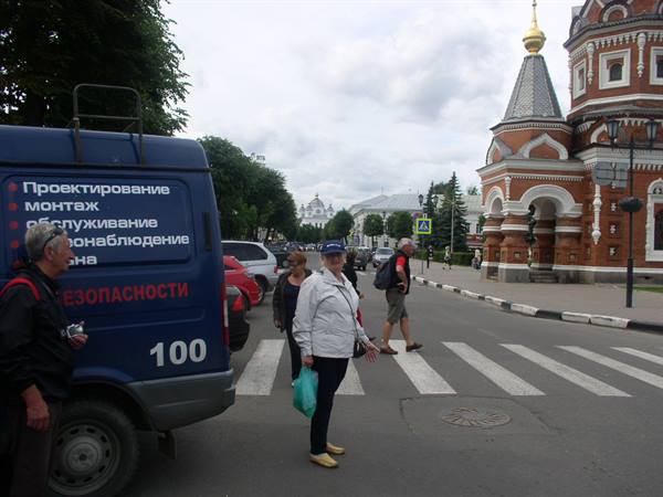 Tourists cross the street by a red brick church in Yaroslavl