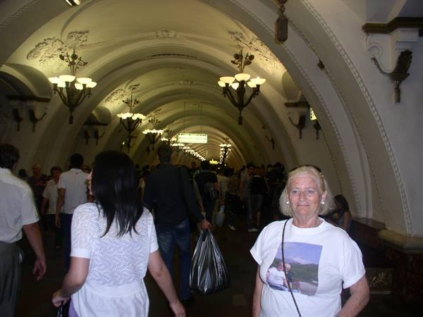 Blonde woman smiles inside Moscow metro station, vaulted ceiling lit by chandeliers