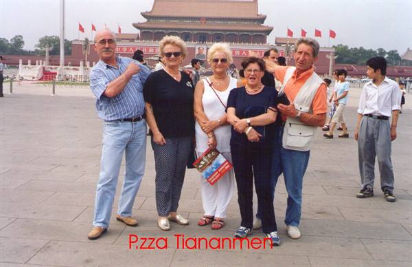 Group of tourists posing on Tiananmen Square, Beijing, with red flags