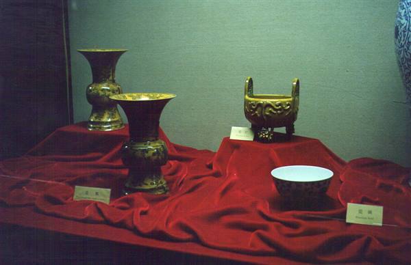 Ceramic vases and censer displayed on red velvet in a museum