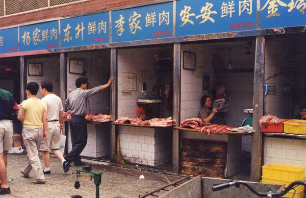 Butcher stalls at a Chinese market, blue signage, customers and vendors at work