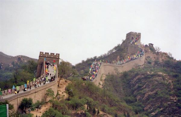 Tourists walking along Great Wall towers and ramparts under grey sky