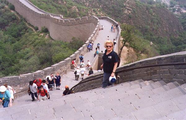 Woman climbing the Great Wall, stone steps, tourists and green hills