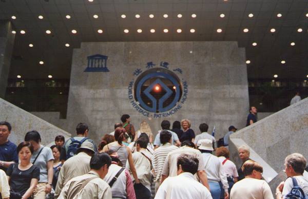 Visitors descending marble stairs beneath the World Heritage emblem indoors