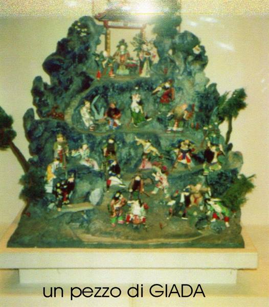 Jade sculpture with carved figures on rocky mountain, displayed in museum case