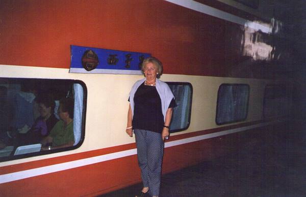 Smiling woman beside a red and white train carriage at night