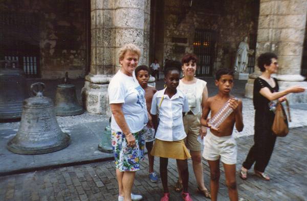 Tourists and children beside large bronze bells in a stone courtyard