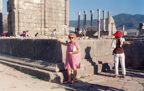 Tourists leaning on Roman walls among columns, Volubilis site
