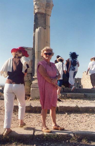 Tourists near an ancient ruined column in the sunlight