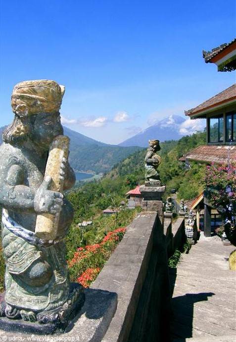 Stone Balinese guardian statue on the wall, Mount Batur volcano behind