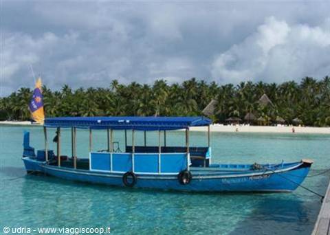 Blue wooden boat moored at the pier, turquoise lagoon and palm-lined beach