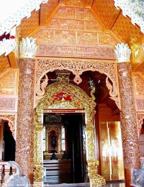 Carved golden wooden temple entrance, decorated columns, Buddha statue inside
