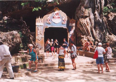 Tourists at the entrance of a Buddhist cave with carvings in the rock