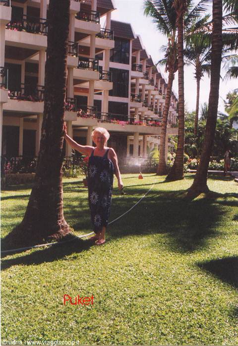 Woman in floral dress beside a palm tree in front of Phuket hotel