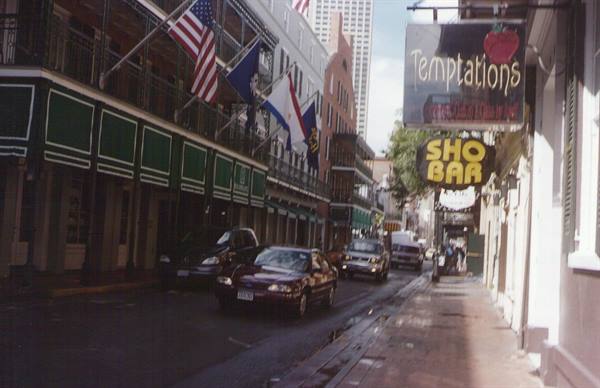 American flags on iron balconies, Sho Bar and Temptations signs, cars on street