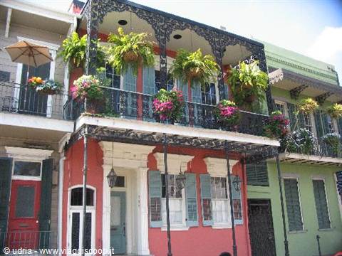 Wrought iron balcony with hanging ferns and pink flowers, French Quarter New Orleans