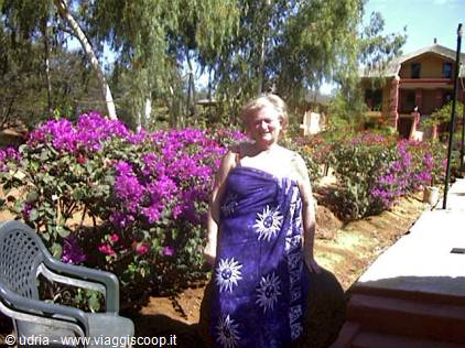 Smiling woman wrapped in a blue sarong among purple flowers