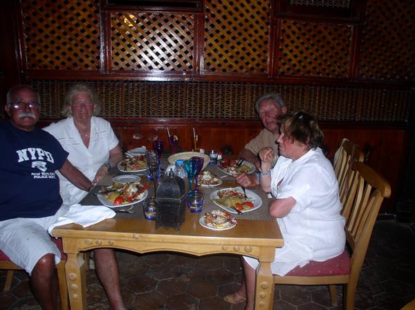 Four people eating shrimp and crab at a wooden table in warm light