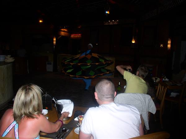Whirling dervish in colorful skirt spins in a dark venue before diners