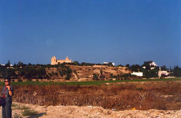 Tourist posing on dry ground, Mdina cathedral in the background