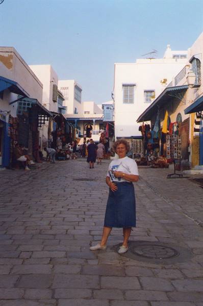Woman in skirt on cobbled street among white houses with blue shutters, Sidi Bou Said