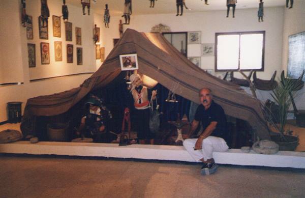 Man sitting in front of a Bedouin tent exhibit in a puppet museum