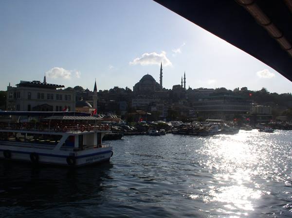 Ferry docked at Eminönü, Süleymaniye Mosque skyline, sunlight glinting on the water