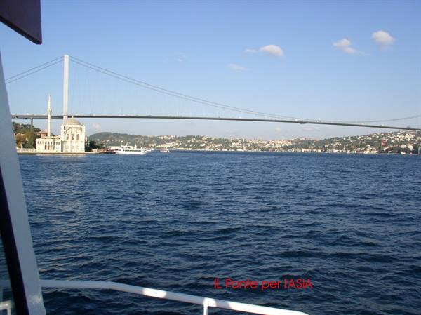 Suspension bridge over the Bosphorus with a mosque by the water, seen from the boat