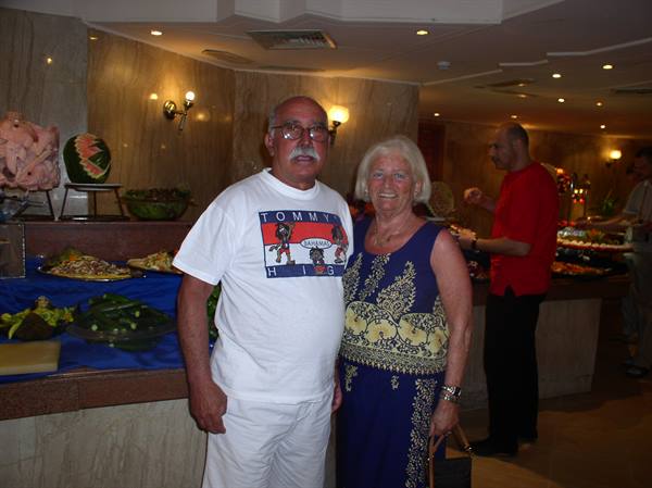 Smiling tourist couple standing in front of the hotel restaurant buffet