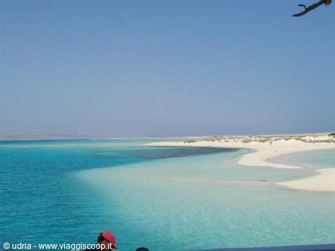 Turquoise lagoon and white sand, a red hat in the foreground