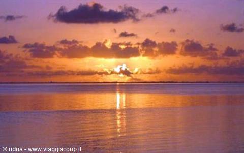 Low sun reflected on calm sea beneath dark clouds