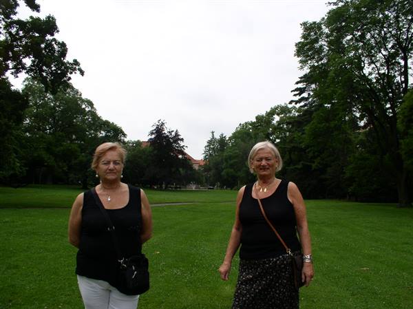 Two women in black tops posing on a green park lawn