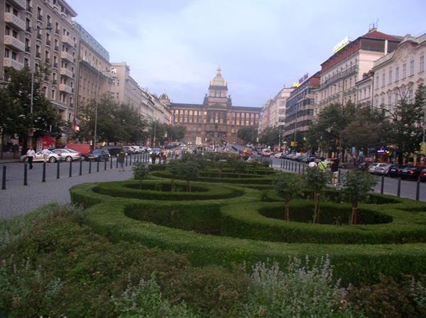 Wenceslas Square with clipped hedges and the lit National Museum in Prague