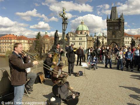 Street musicians on Charles Bridge in Prague, tourists listening under a cloudy sky
