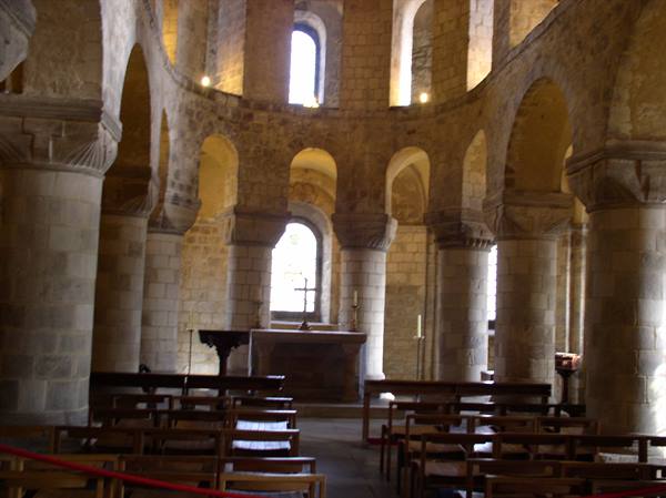 Norman stone chapel with columns, arches and wooden pews, light through windows