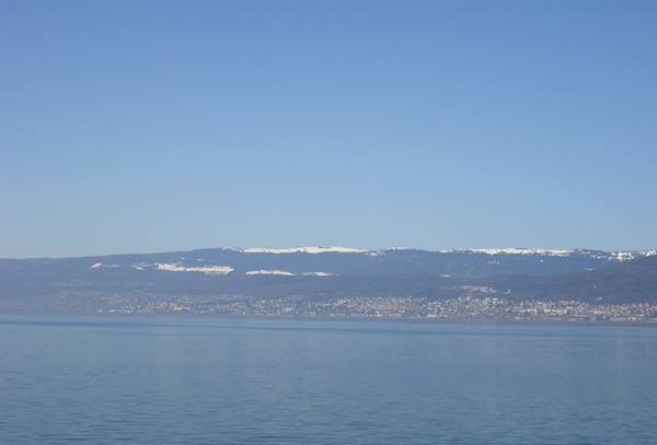 Calm lake water in front of snowy hills and shoreline towns