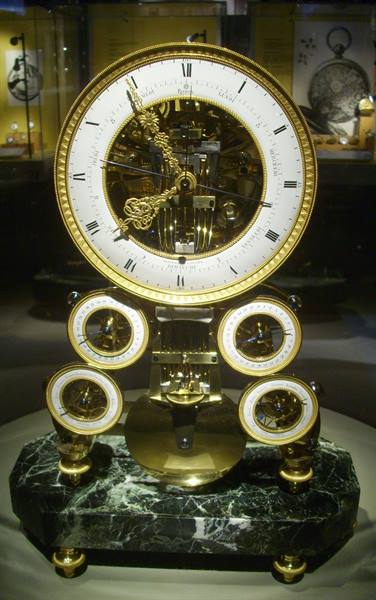 Gilt bronze clock with skeleton movement on green marble base, museum display