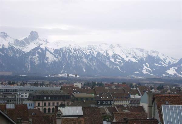 Bern rooftops beneath snow-capped Alps on an overcast day