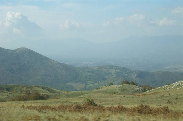 Grassy hills with autumn ferns, misty mountains and valley with distant villages